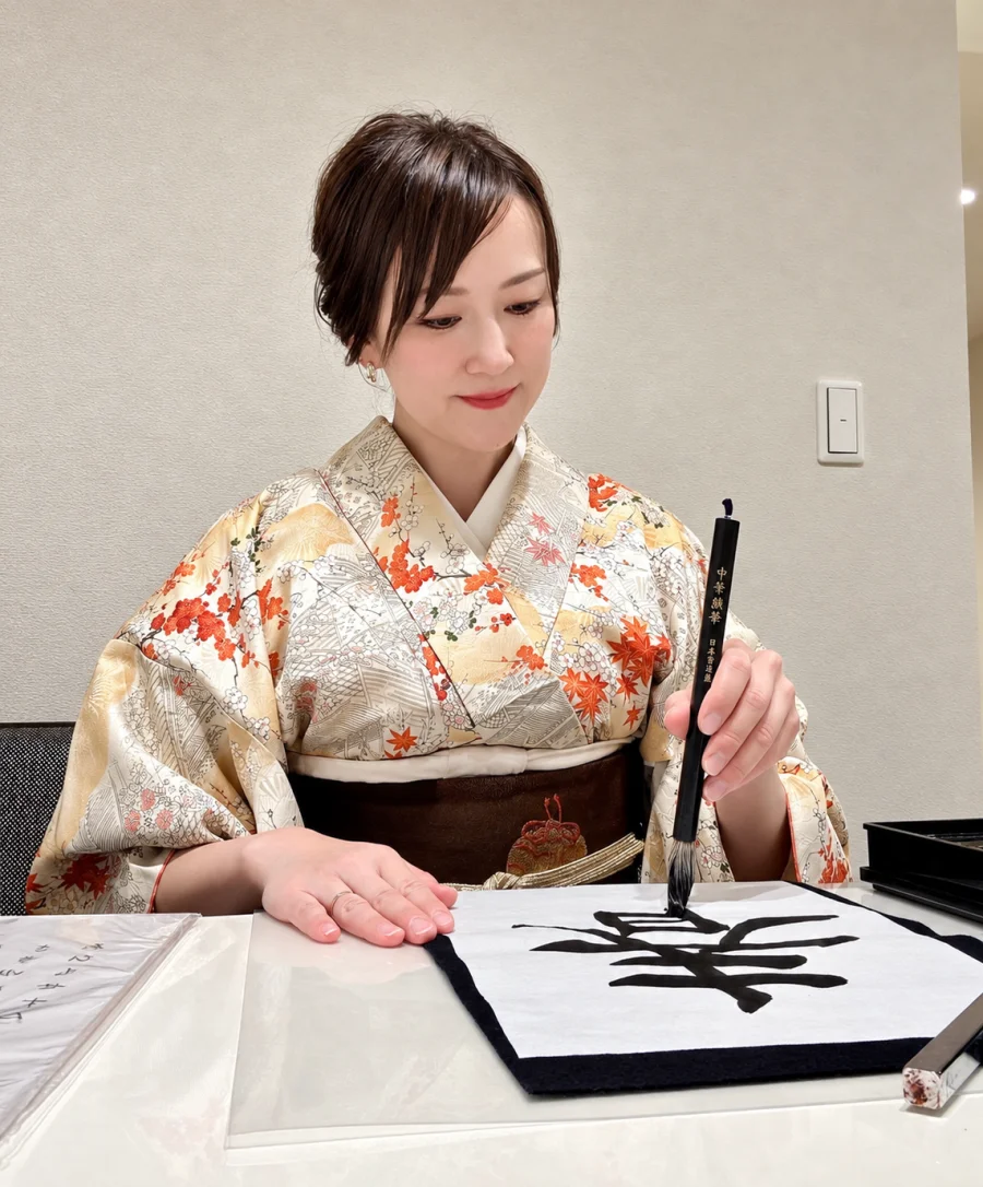 着物姿で筆を持ち、作品を書く谷 弥生さん