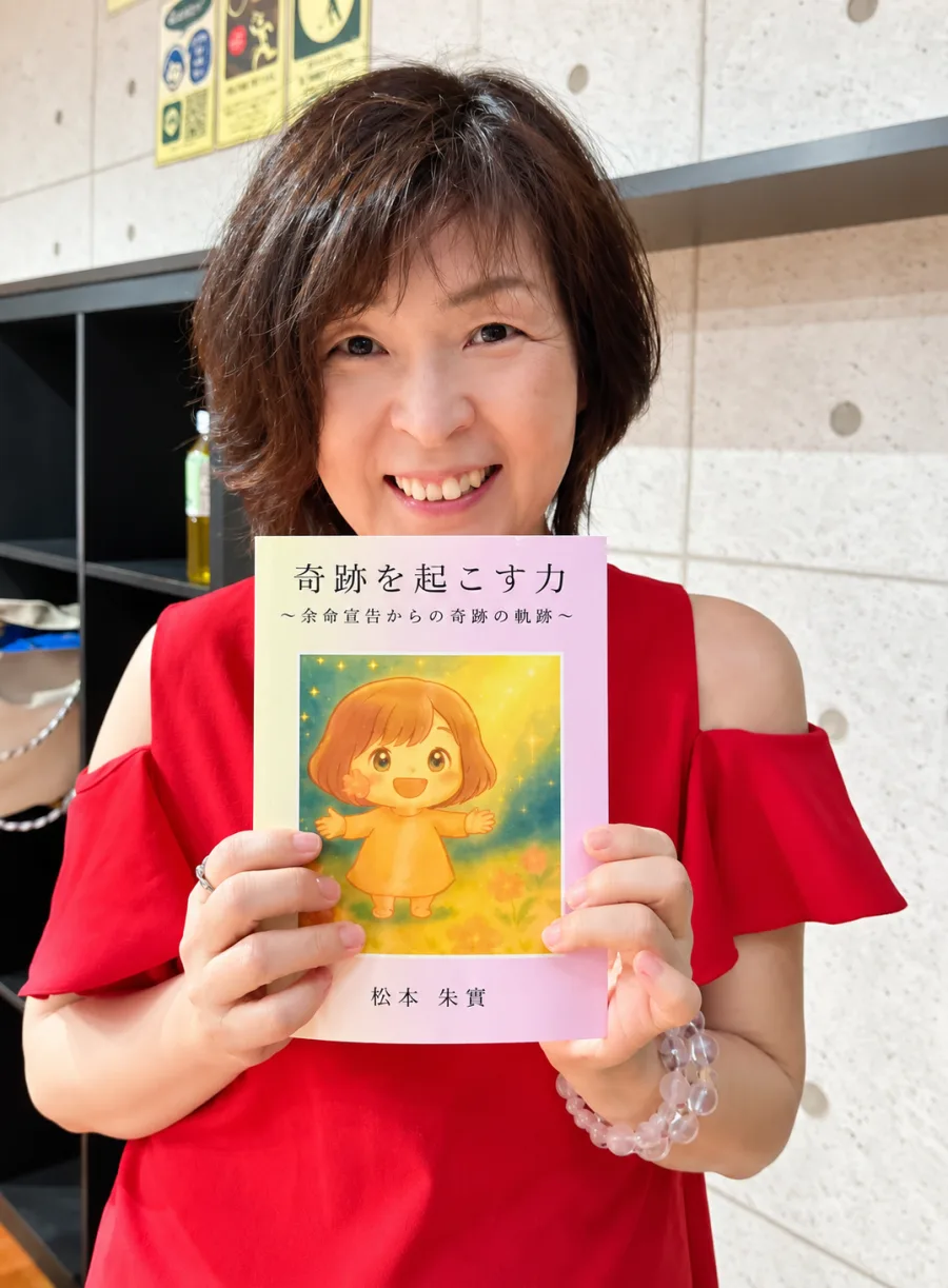 著書『奇跡を起こす力〜余命宣告からの奇跡の軌跡〜』を手にするあけみんさん